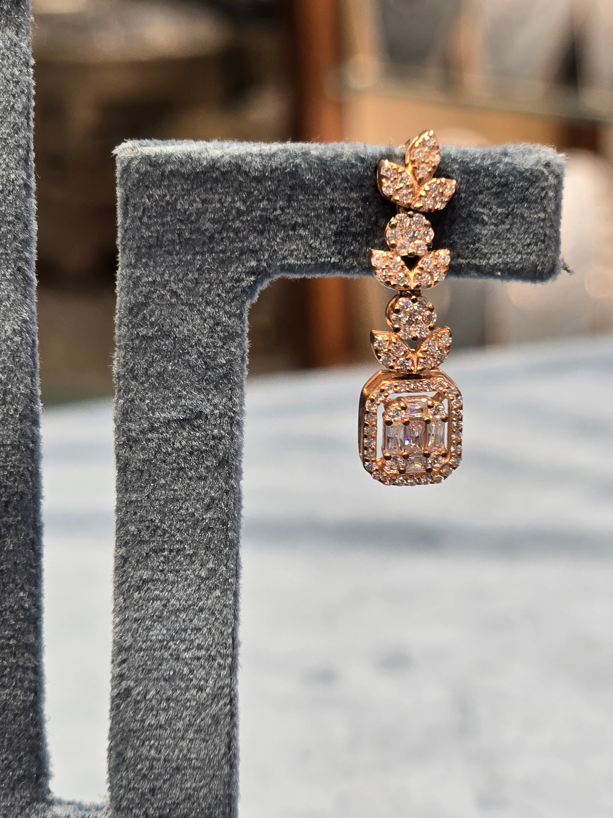 Rose gold silver ring with diamond accents on a gray stand.