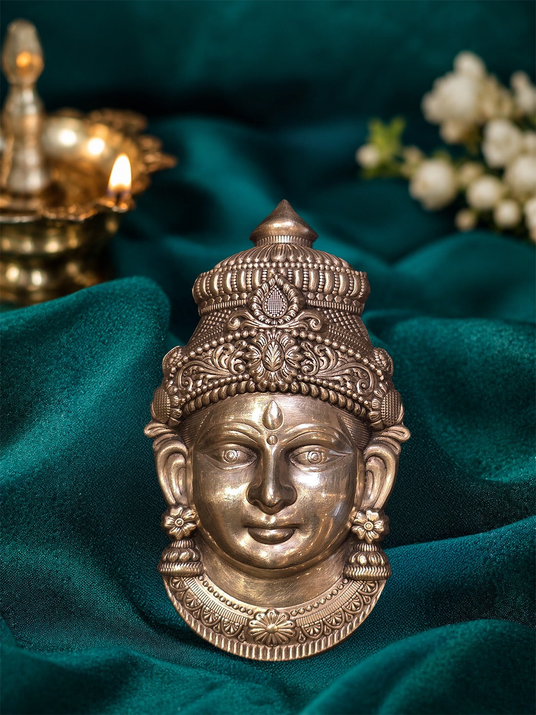 Silver Lakshmi idol face with ornate crown, embossed jewelry, calm eyes