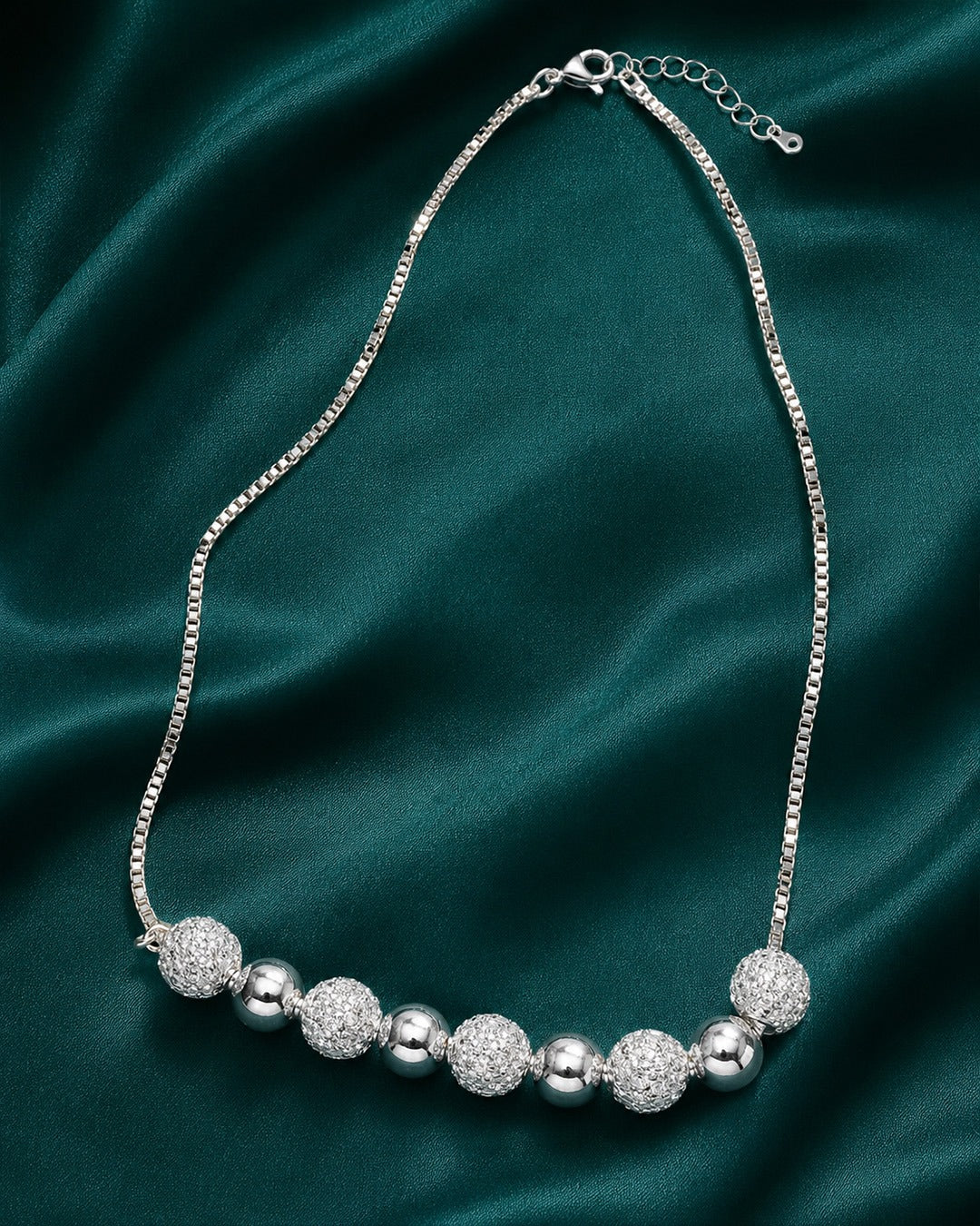 Silver beaded bracelet on a dark green fabric background