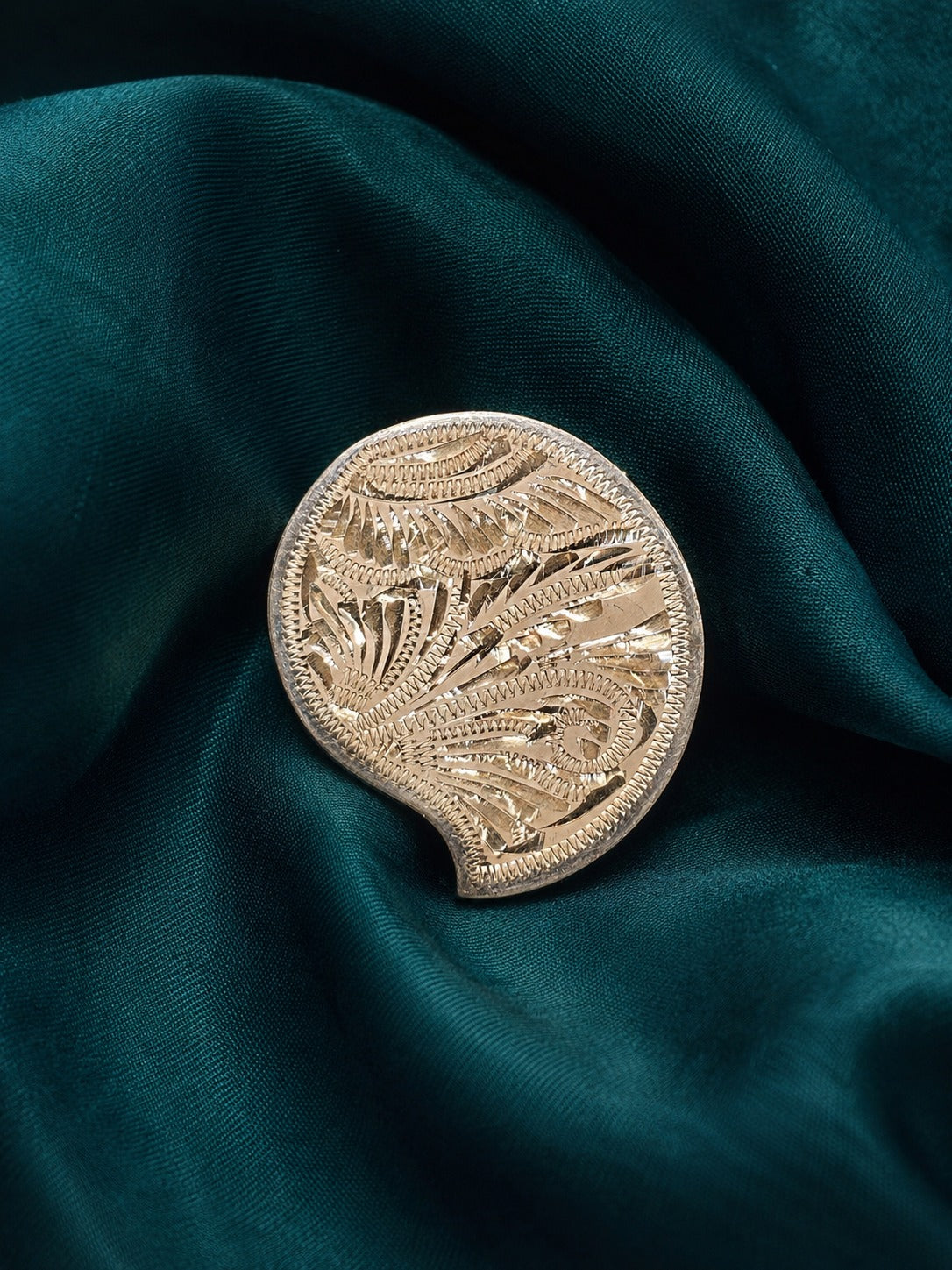 Small embossed gold-tone kumkum box with floral medallion design and curved base