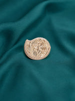 Round embossed gold-tone pooja kumkum box with floral border motif and textured rim