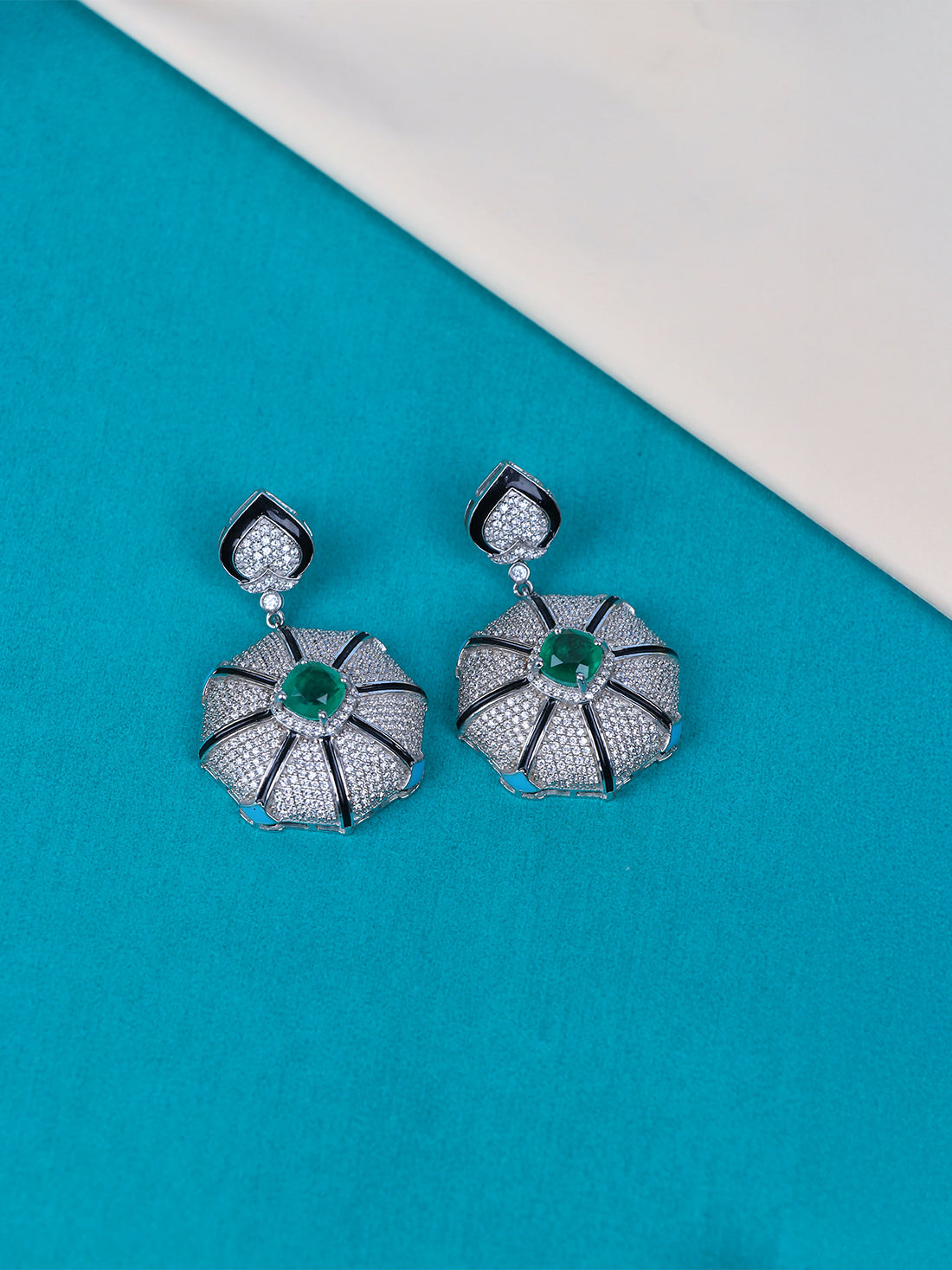 Shop a pair of silver dangle earrings with textured pave floral drops and central green stone accents.
