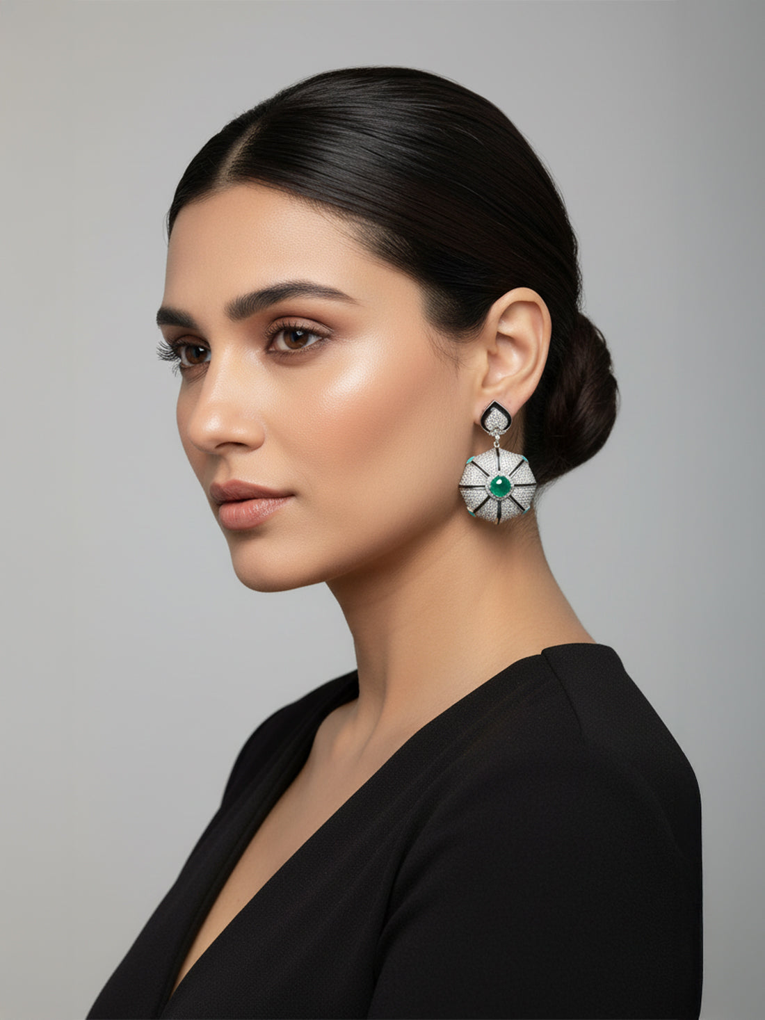 Shop worn silver drop earrings featuring a flower-shaped pave setting with a central green emerald and a small light blue stone at the base.