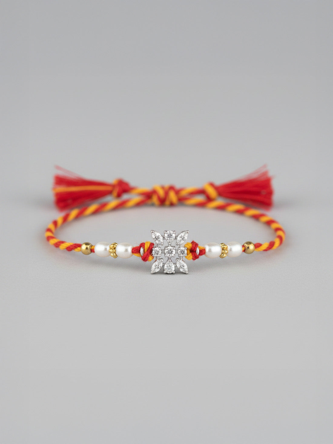 Sterling silver floral rakhi with pearl beads, red-yellow braided thread and tassel