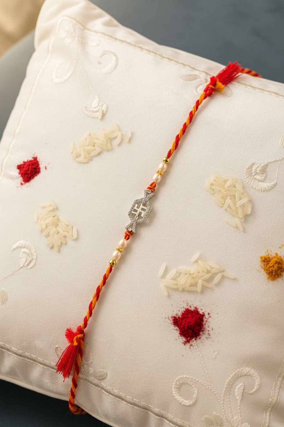 Sterling silver swastik rakhi with pearl beads, red twisted thread and tassel