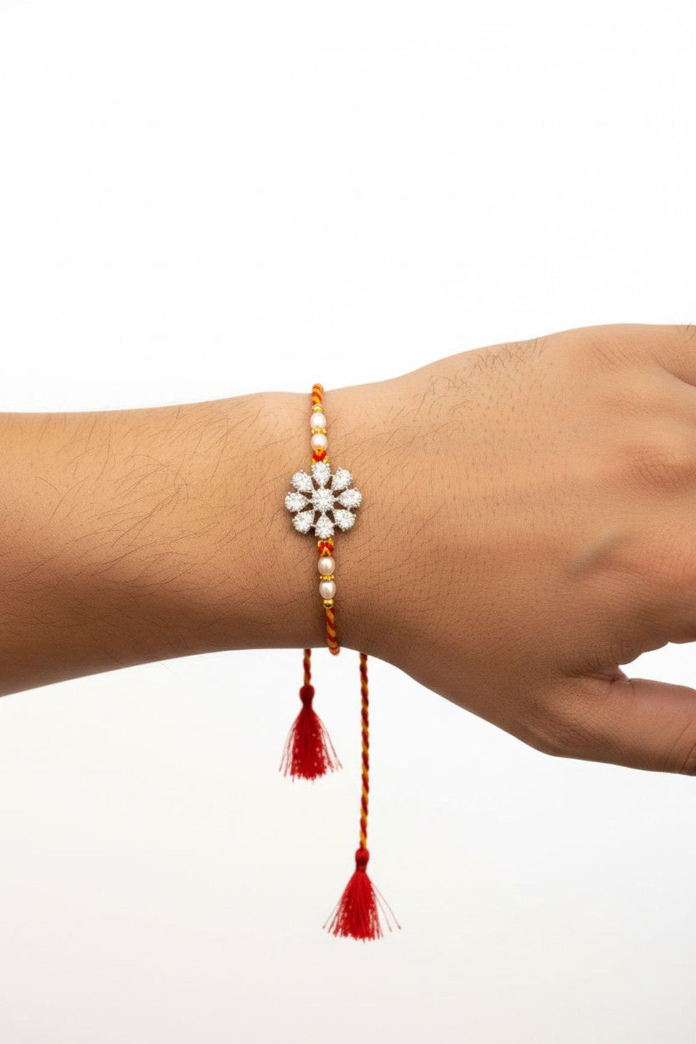 Sterling silver flower rakhi on wrist with red-yellow thread and hanging red tassels
