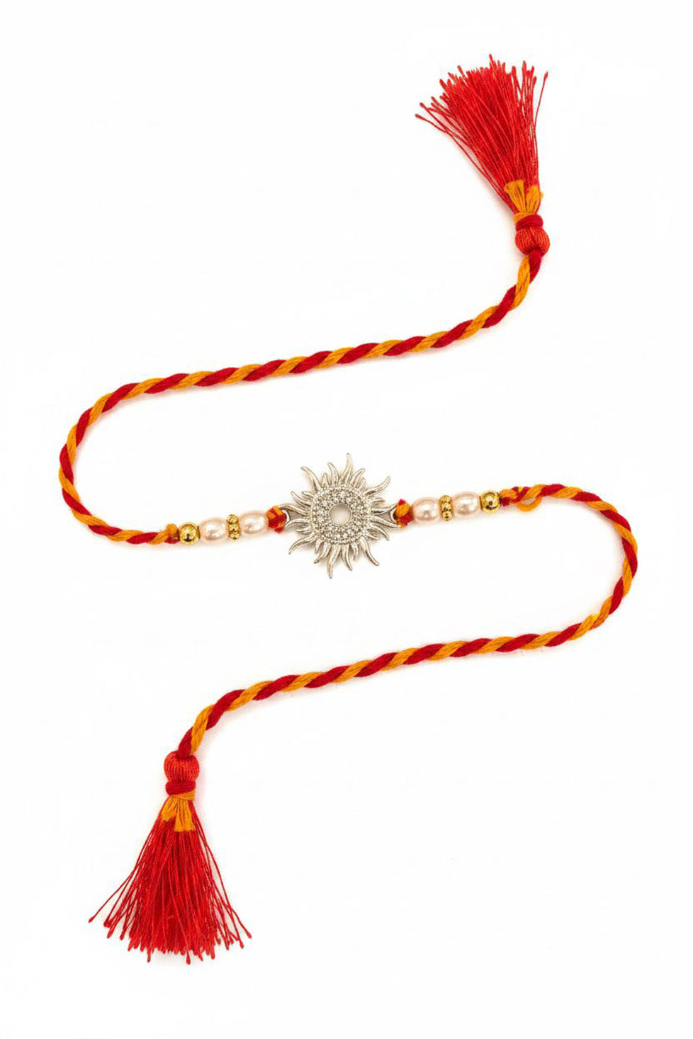 Red and yellow braided rakhi with silver sun motif charm, pearl beads, and tassels