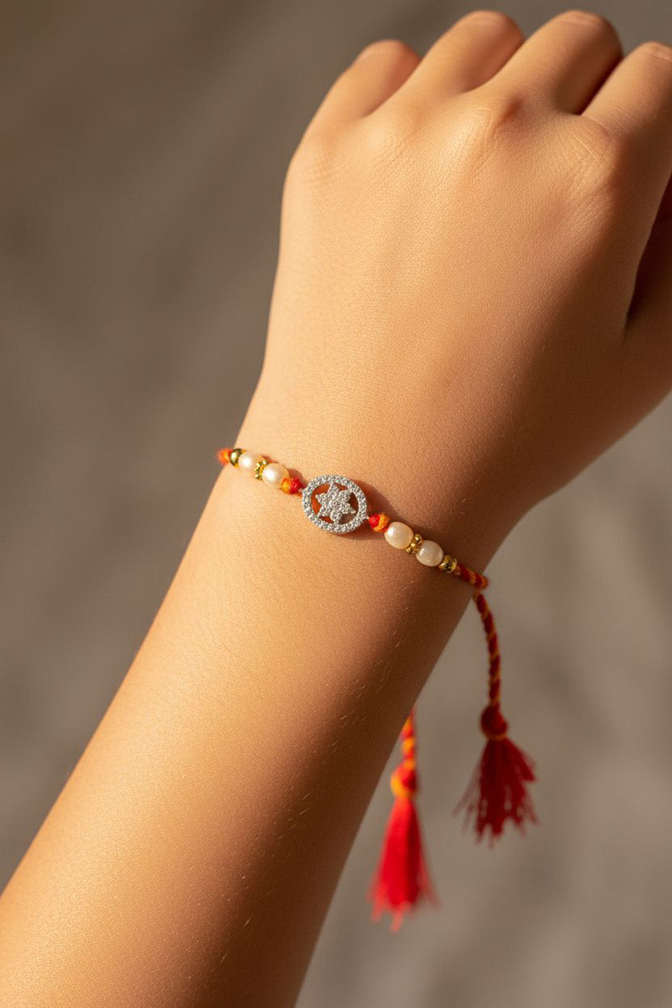 Sterling silver floral disc rakhi bracelet on wrist, red thread, pearl beads, tassel
