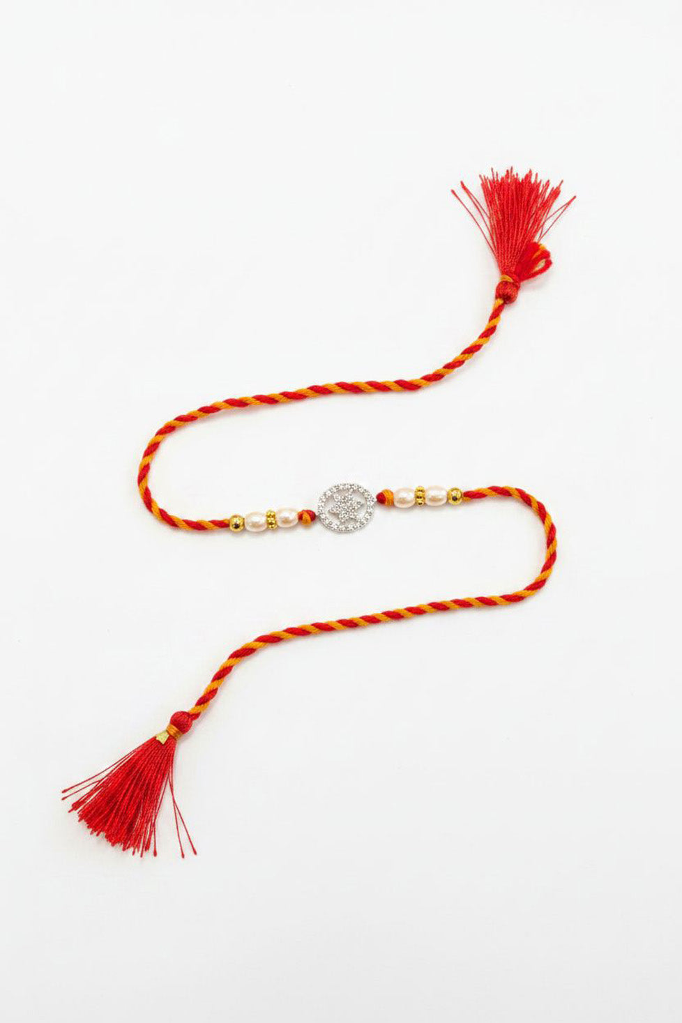 Sterling silver floral disc rakhi with red thread, pearl beads, and tassels