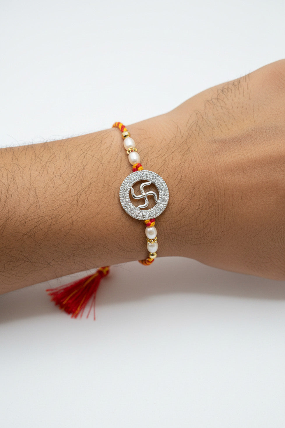 Sterling silver rakhi with circular swastik charm, pearl beads, red-yellow thread, tassel