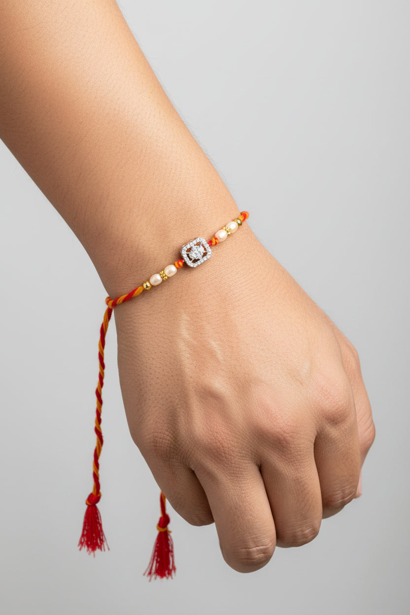 Square floral silver rakhi bracelet with pearl beads, orange-red striped thread and tassels