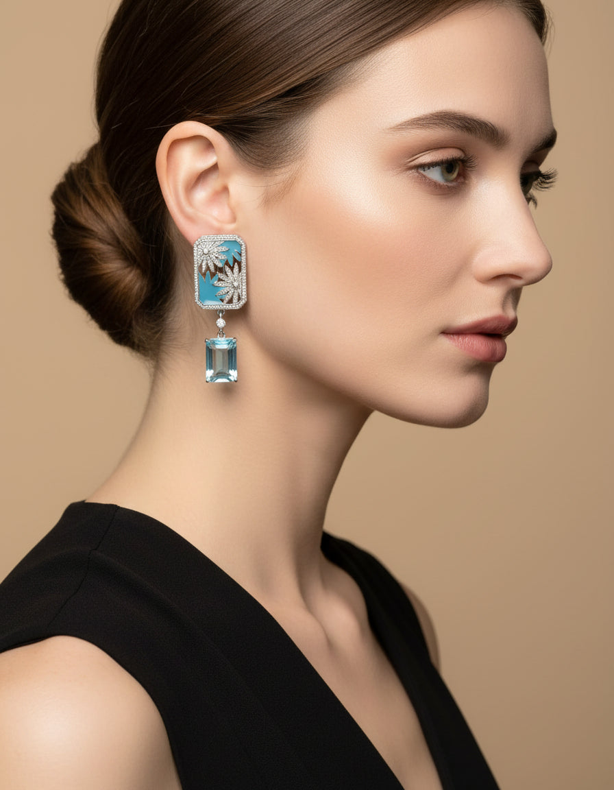 Woman wearing ornate blue silver earrings with floral detailing and rectangular aqua drop stones.