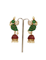 Close-up of traditional dangling earrings with green enamel leaves and red tassels