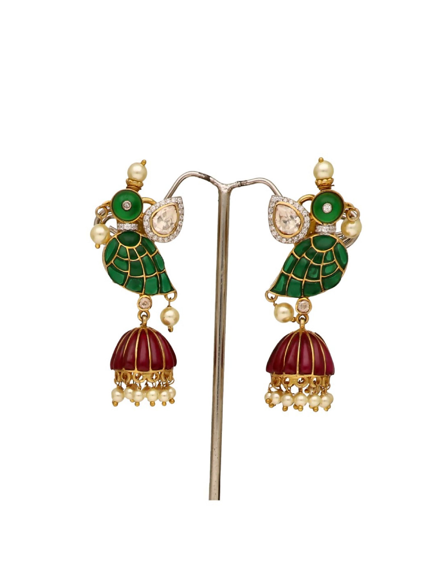 Close-up of traditional dangling earrings with green enamel leaves and red tassels