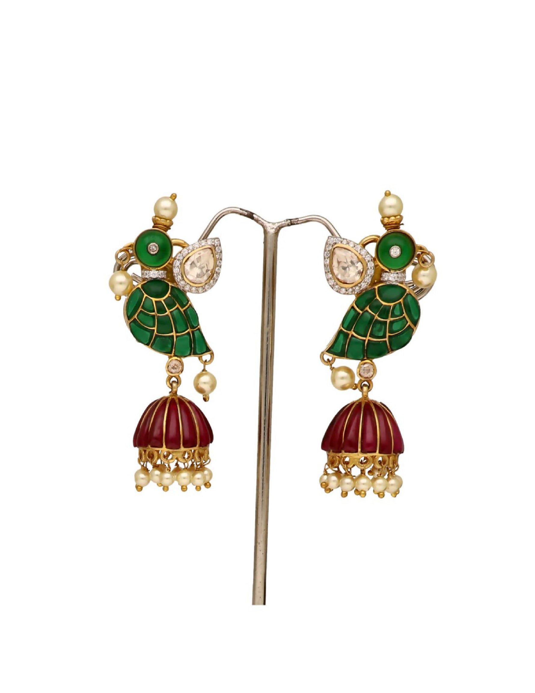 Close-up of traditional dangling earrings with green enamel leaves and red tassels