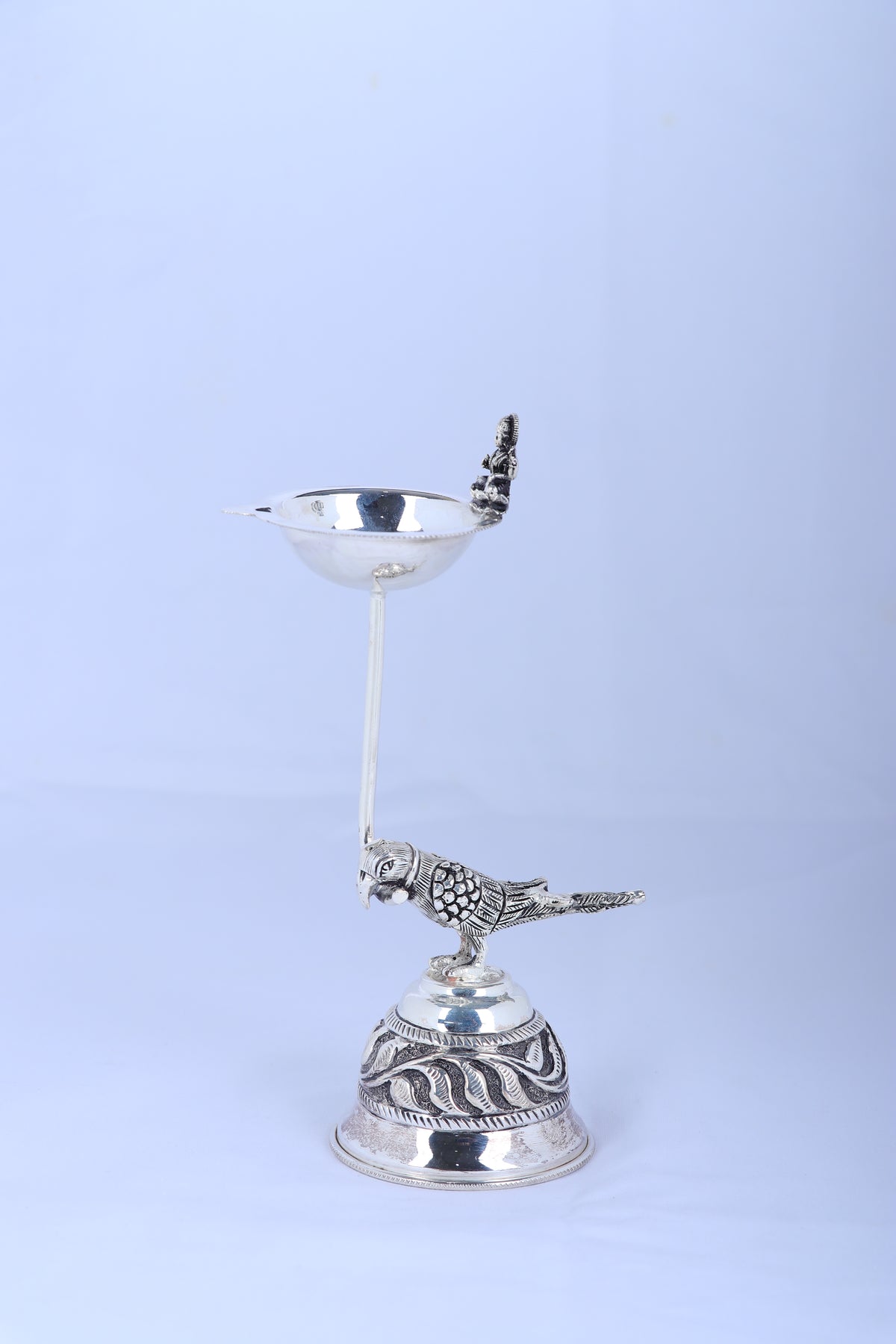 Silver-tone pooja diya lamp with top bowl, bird figurine, and ornate rounded base