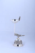 Silver-tone pooja diya lamp with top bowl, bird figurine, and ornate rounded base
