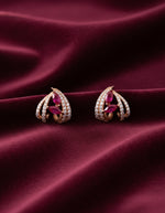Designer silver stud earrings with ruby-coloured stones and sparkling leaf-shaped crystal detailing.