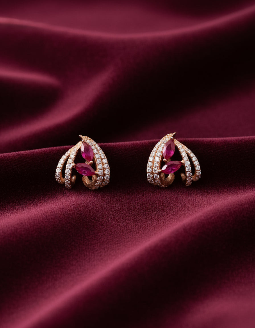 Designer silver stud earrings with ruby-coloured stones and sparkling leaf-shaped crystal detailing.