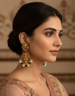 Woman wearing antique-finish silver earrings with Ganesha motifs, green beads and elegant pearl drops.