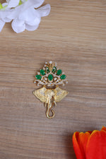 Designer silver brooch featuring a Ganesha motif pinned to a sherwani with green stone details.