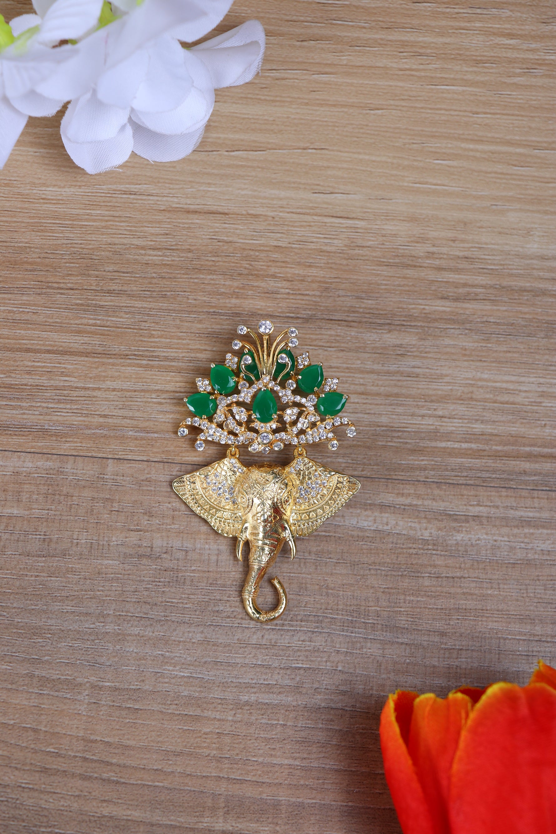 Designer silver brooch featuring a Ganesha motif pinned to a sherwani with green stone details.