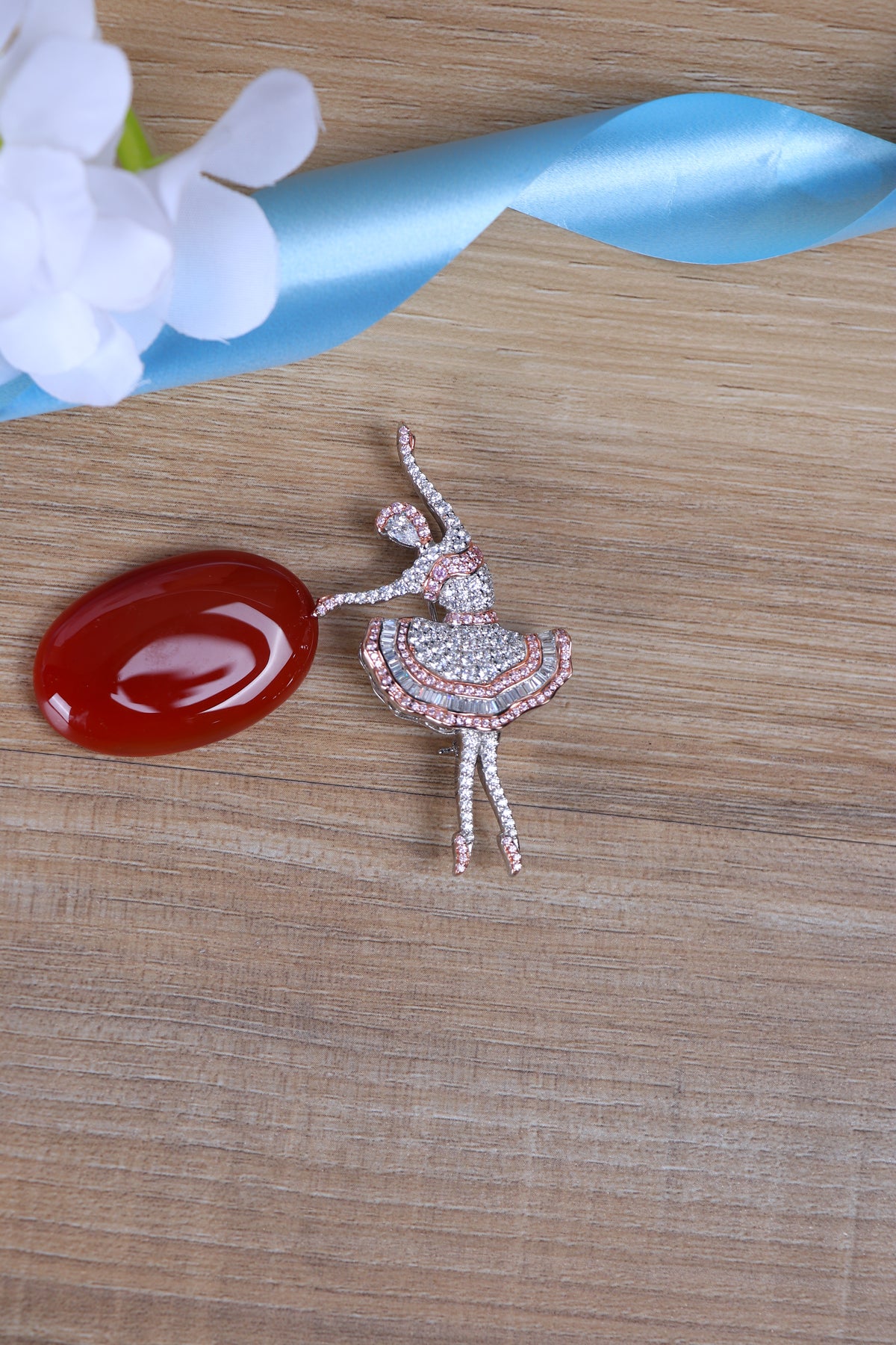 Designer silver brooch featuring a crystal-studded dancer motif pinned to a suit jacket.