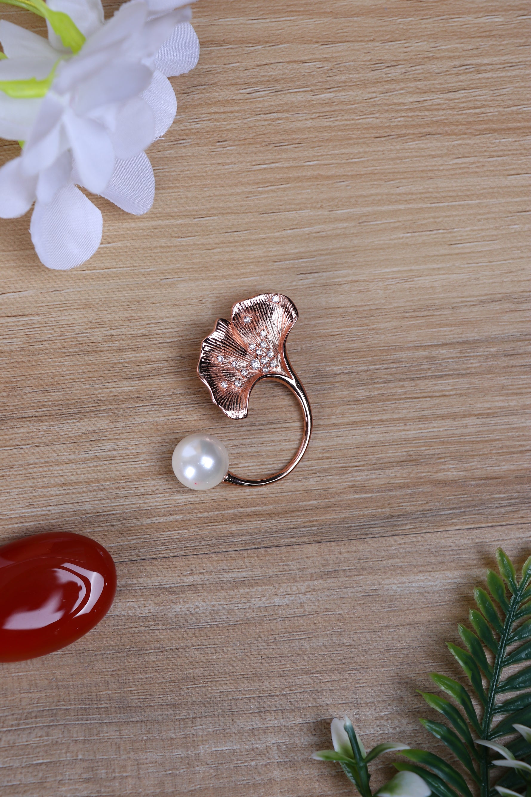 Designer silver brooch featuring a leaf motif with pearl detail pinned to a suit jacket.