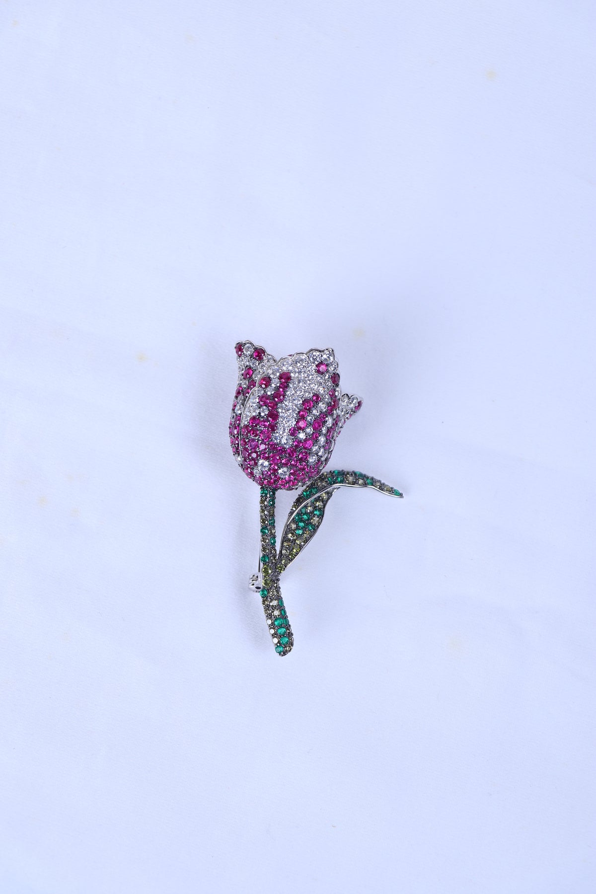 Designer silver brooch featuring a pink rose motif pinned to a sherwani pocket.