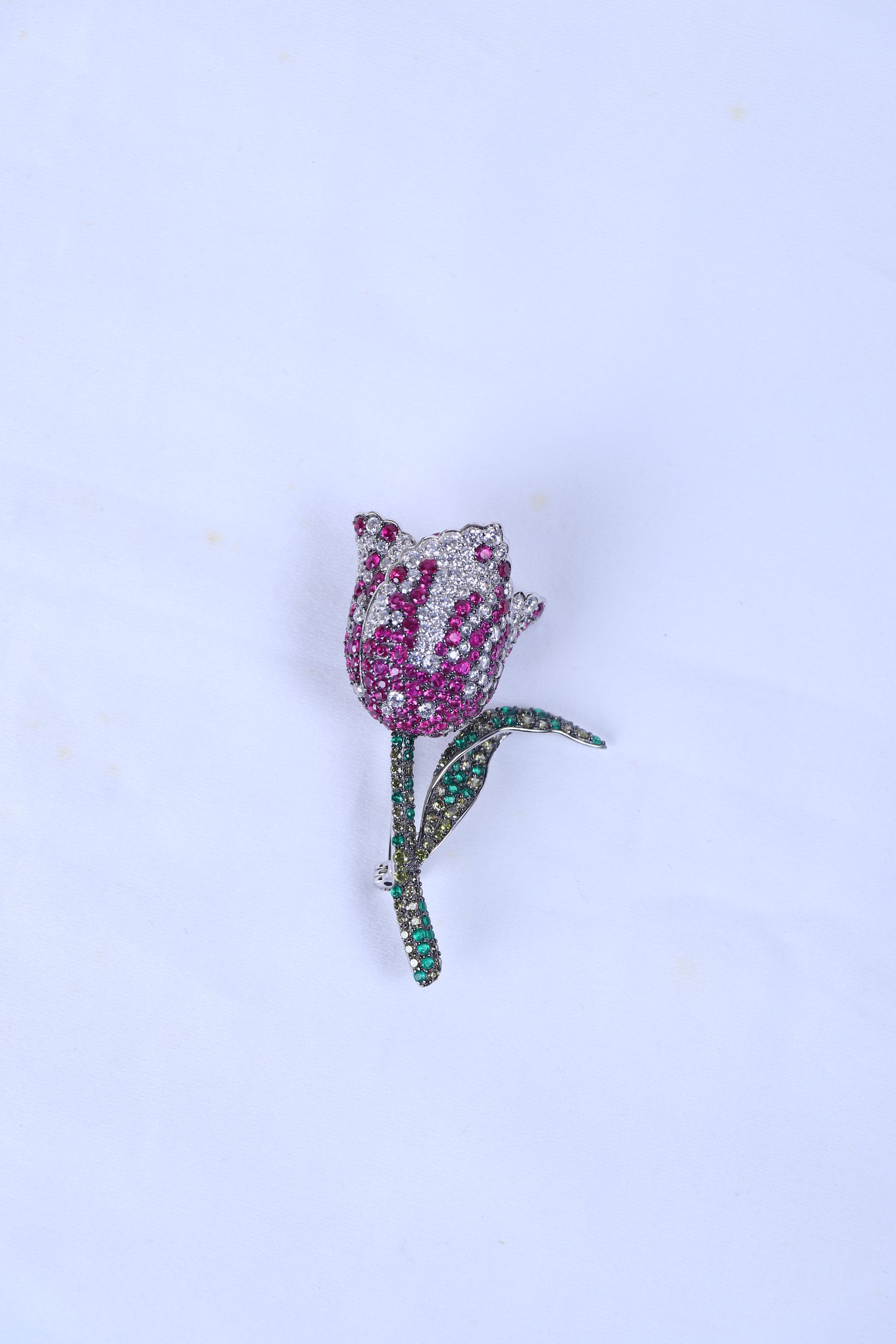 Designer silver brooch featuring a pink rose motif pinned to a sherwani pocket.