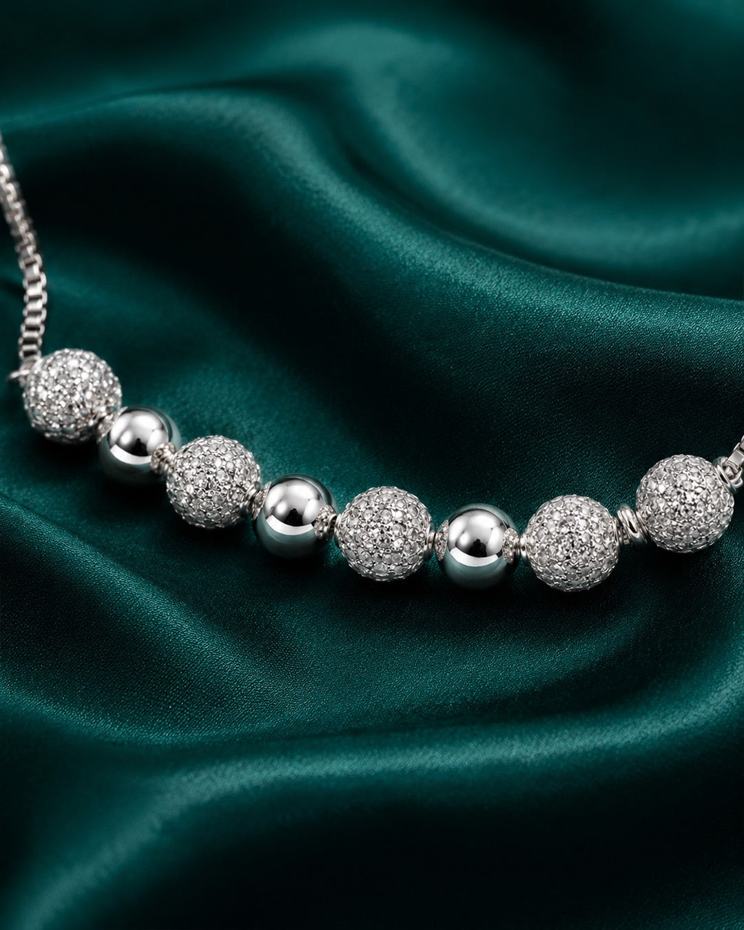 Silver beaded bracelet on a green satin background