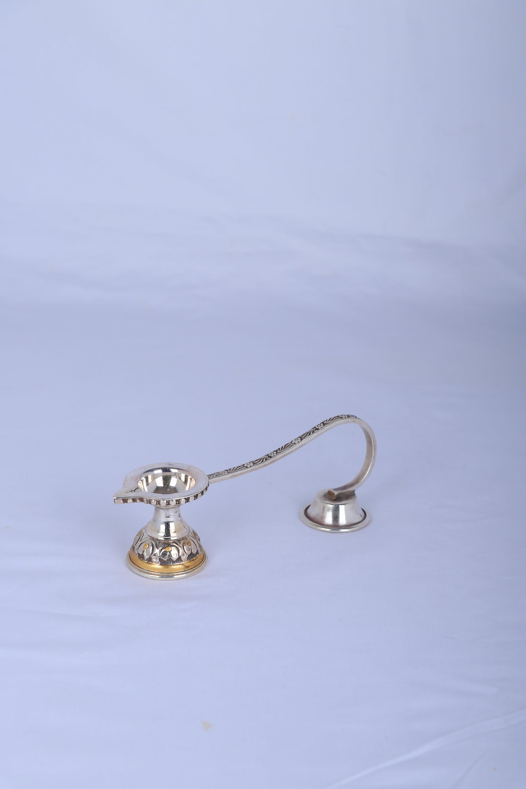 Silver-plated aarti diya oil lamp with two cup holders, angled view