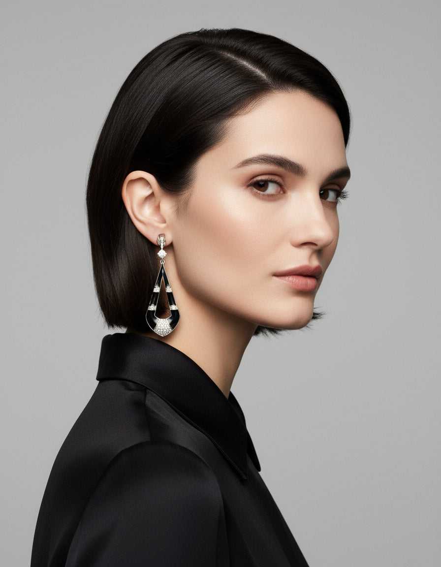 Pair of geometric silver dangle earrings with polished black enamel panels and stone-studded details.