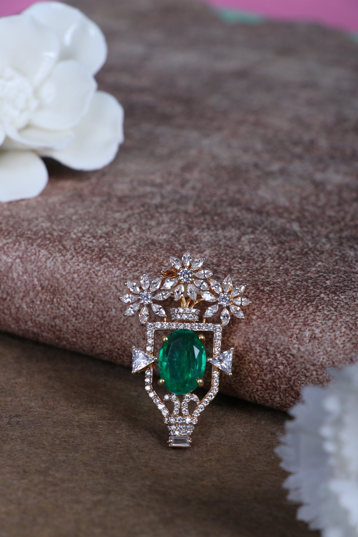 Green oval gemstone silver brooch with glittering crown details on fabric