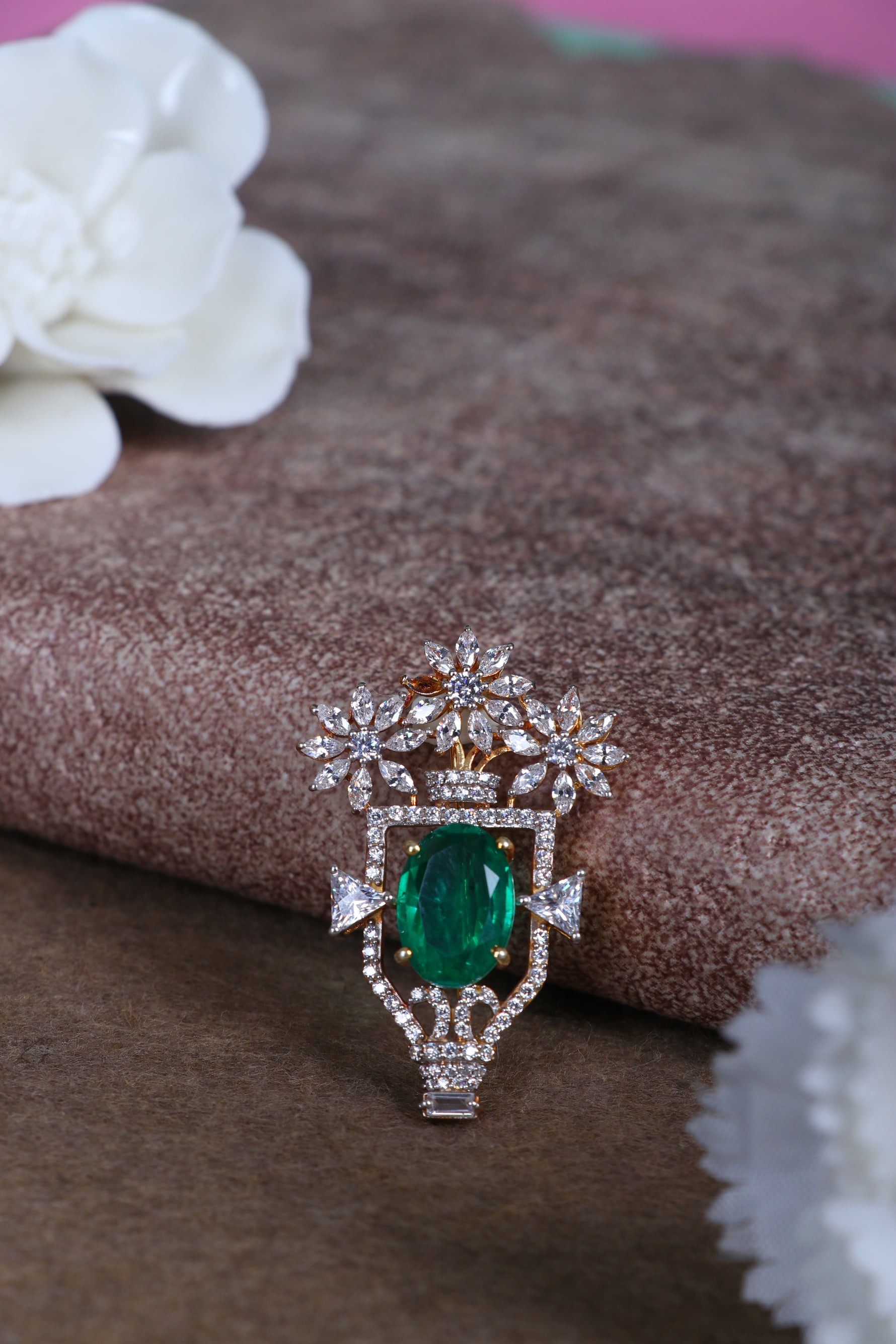 Green oval gemstone silver brooch with glittering crown details on fabric