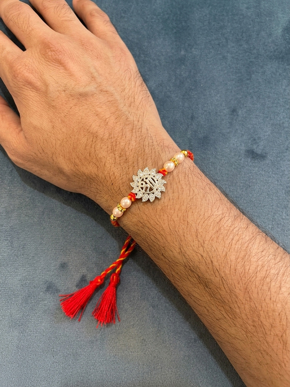 Sterling silver lotus motif rakhi bracelet with pearl beads, red thread and tassel