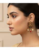 Antique-finish silver earrings for women with intricate deity work, green stones and hanging pearls.