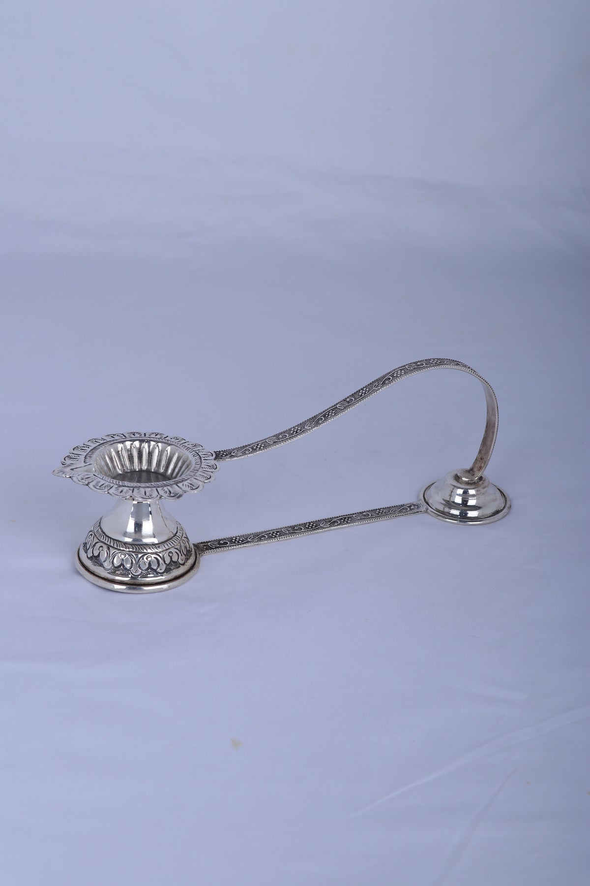 Silver aarti diya lamp with curved handle, lotus-petal wick holder, round base