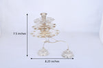 Multi-tier silver aarti lamp with stacked plates and two diya holders, full view
