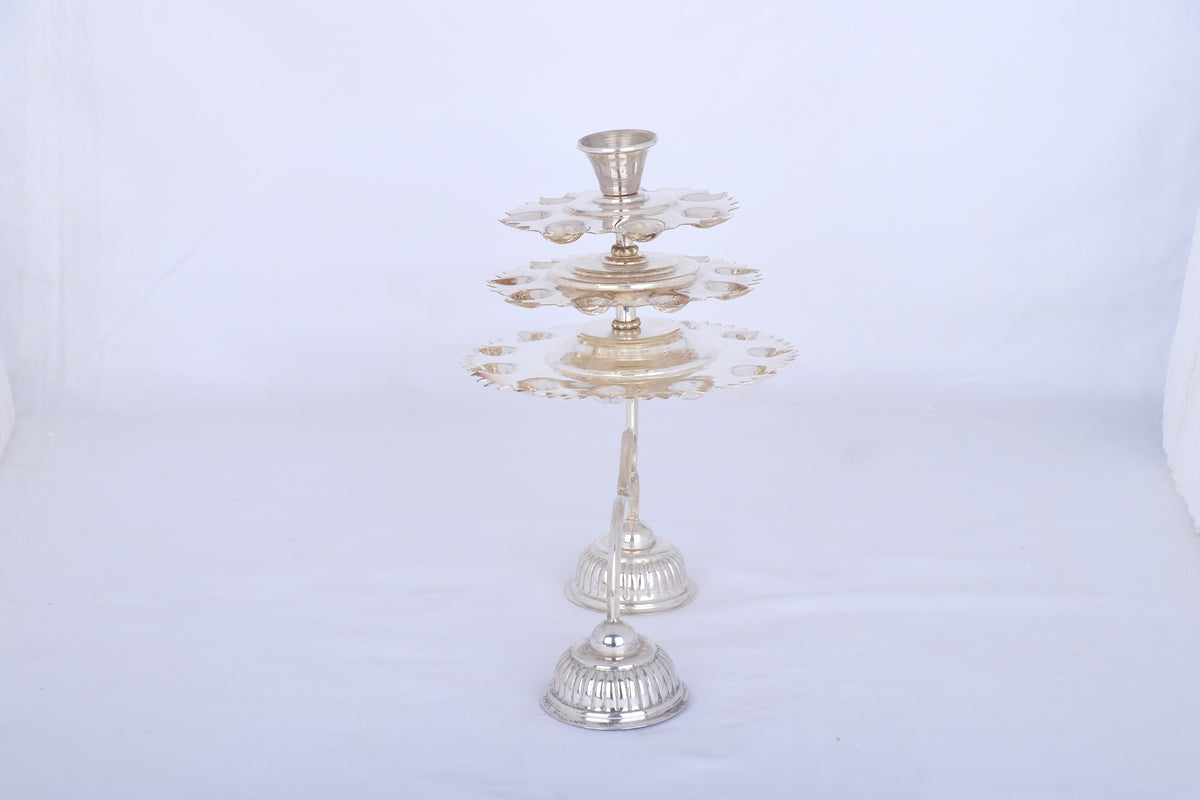 Silver multi-tier aarti lamp on round base with central stem and top cup