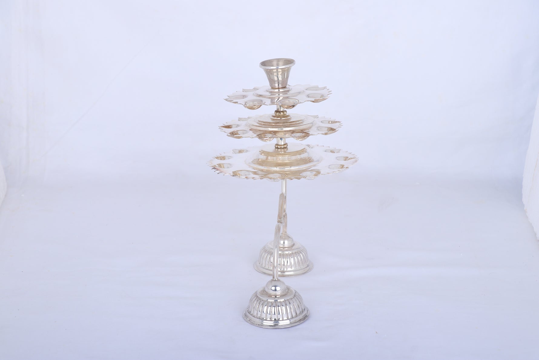 Silver multi-tier aarti lamp on round base with central stem and top cup