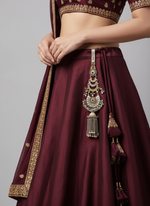 Ornate silver keychain pendant with tassel, on maroon traditional skirt