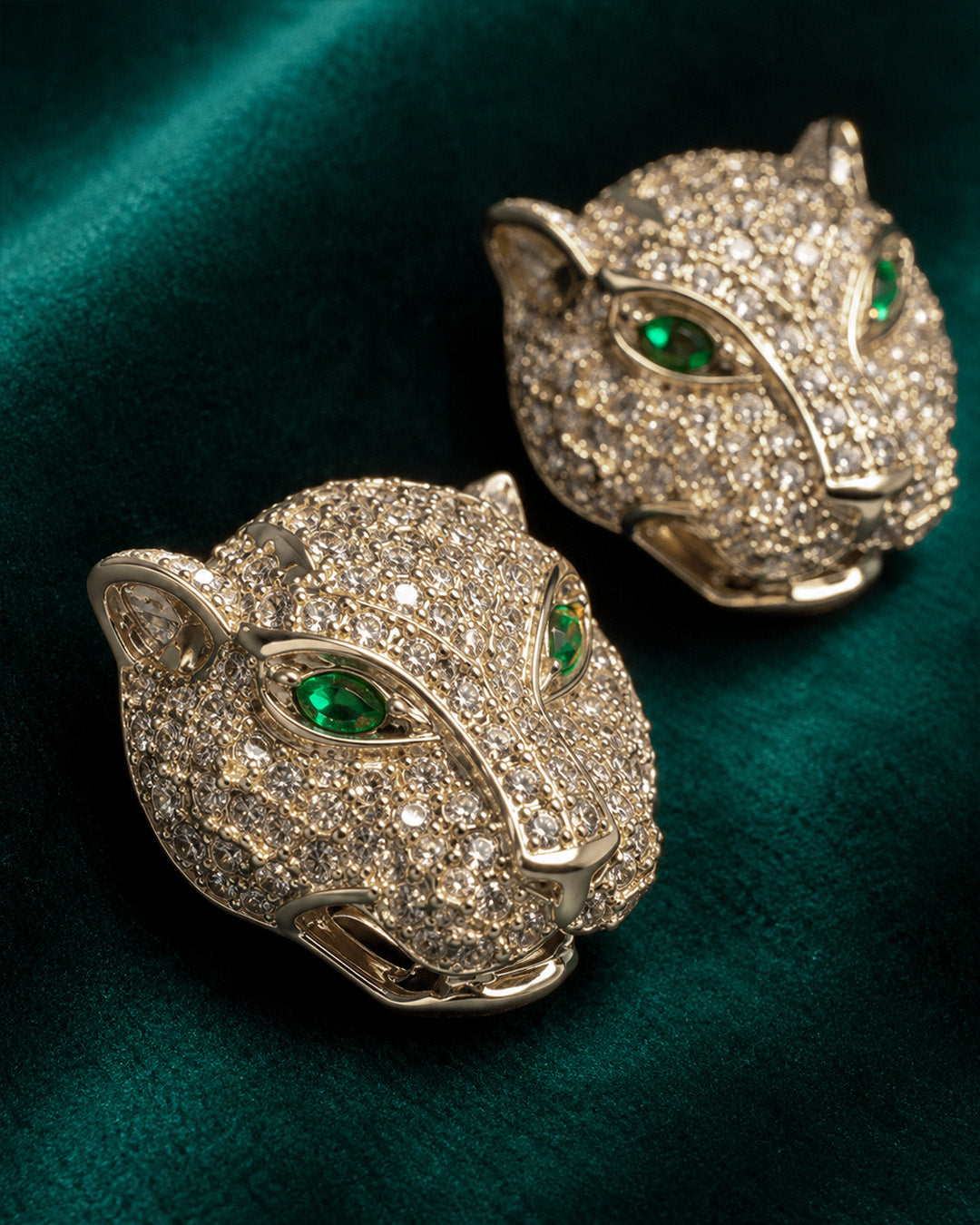 Pair of panther head silver earrings with green gemstones.
