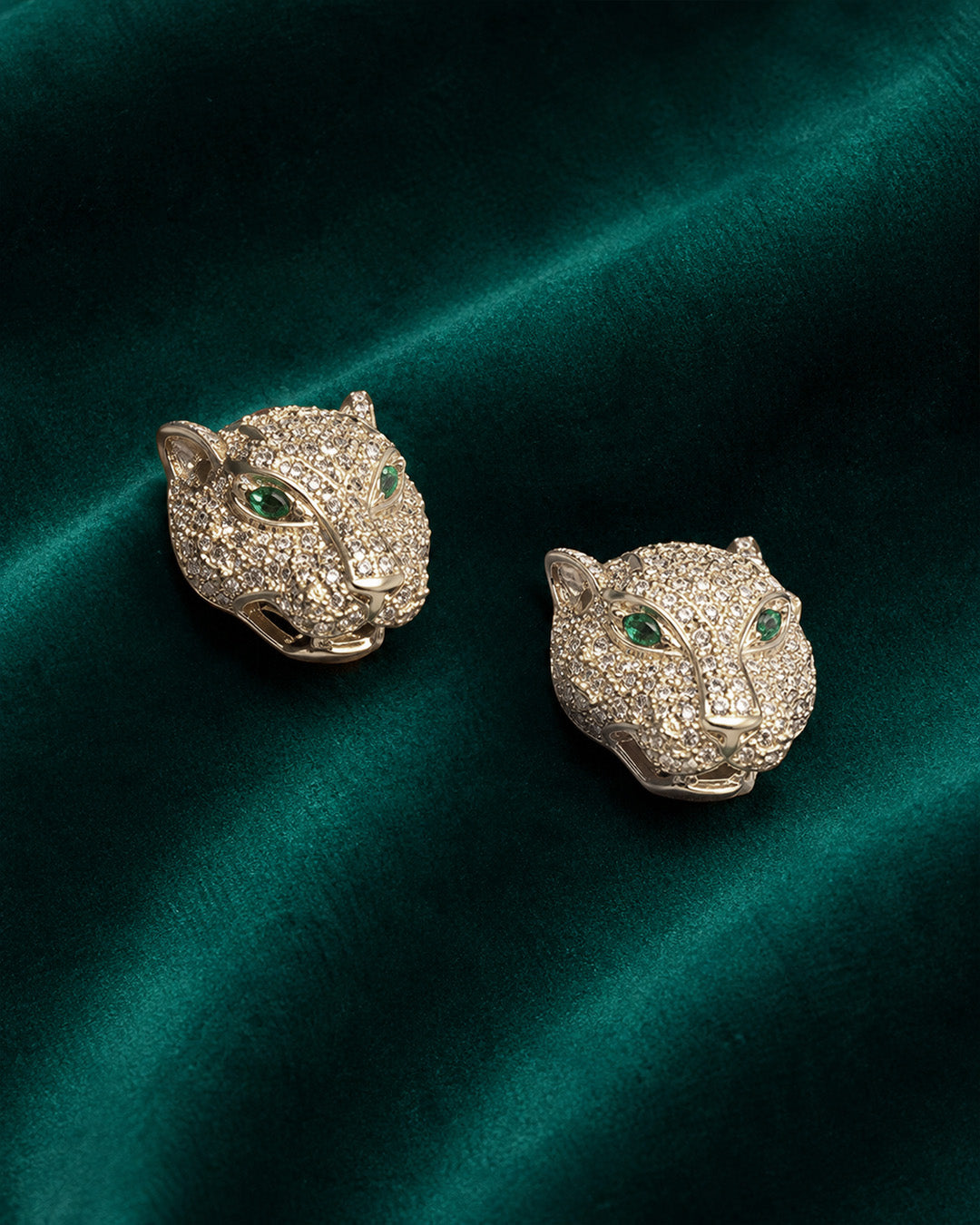 Panther head silver earrings with green gemstones.