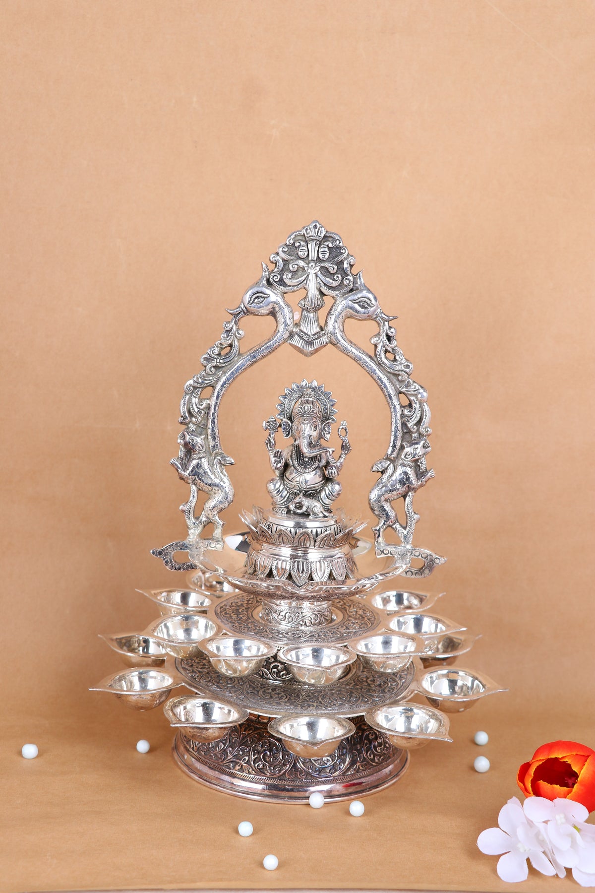 Silver Ganesha pooja diya stand with central idol and stacked diya bowls