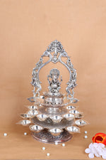 Silver Ganesha pooja diya stand with central idol and stacked diya bowls