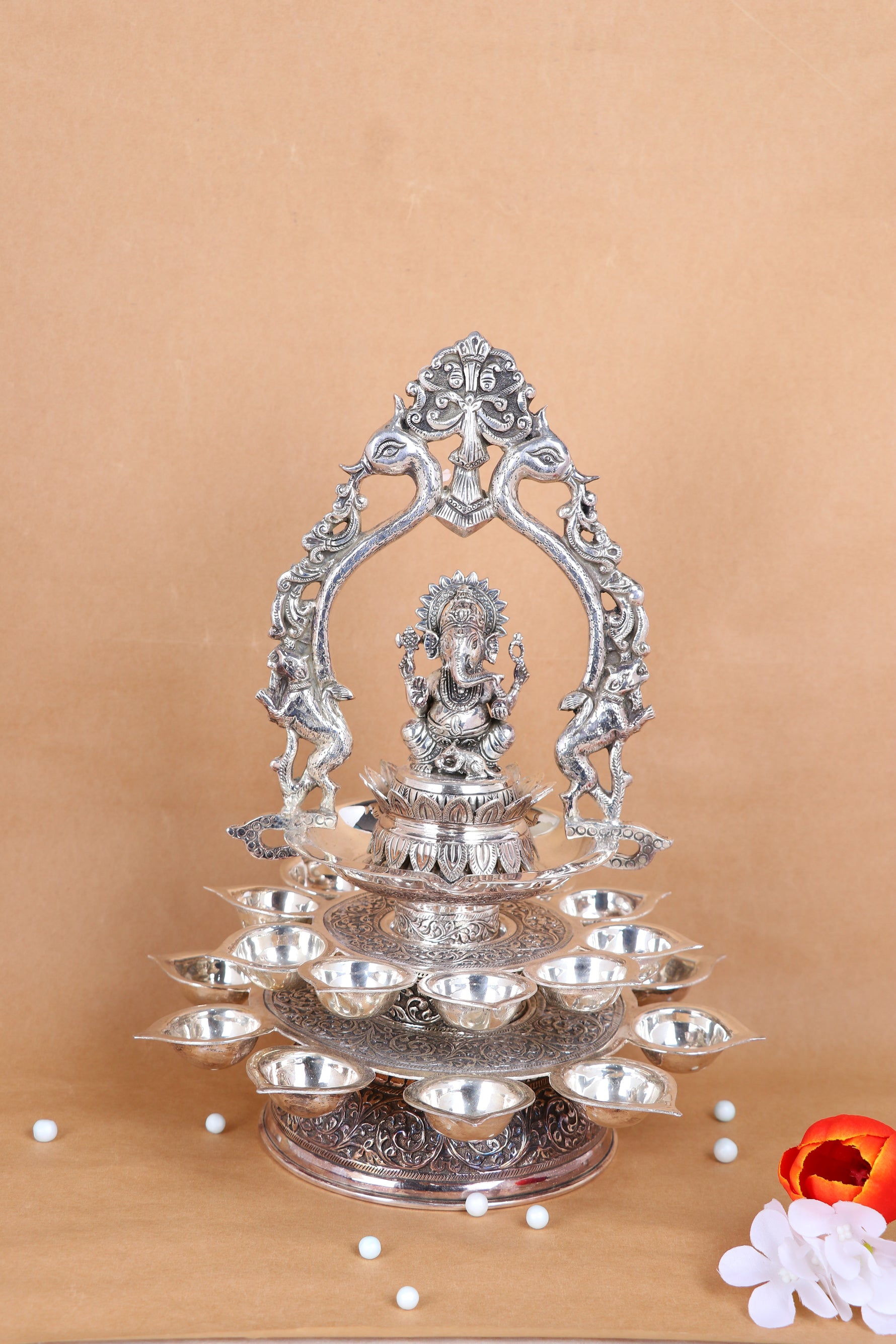 Silver Ganesha pooja diya stand with central idol and stacked diya bowls