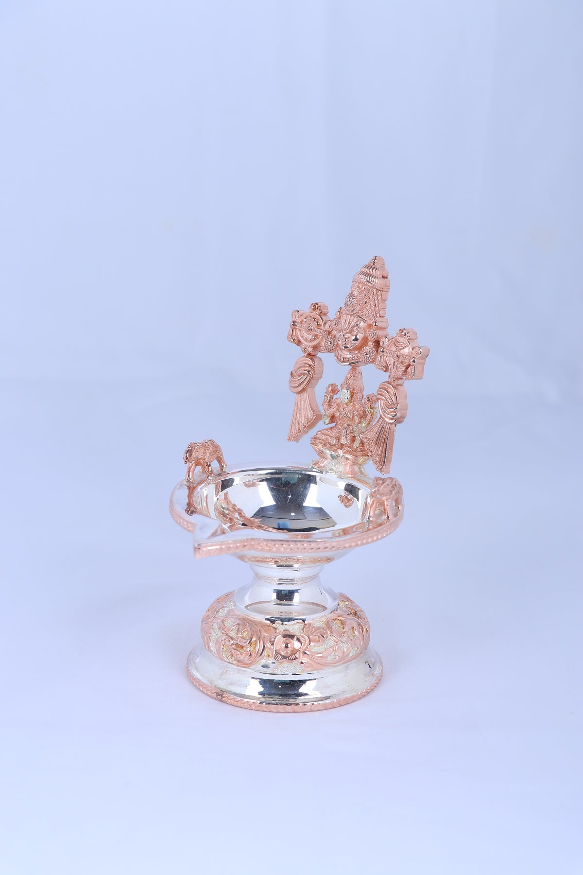 Side view of silver-toned Lakshmi diya with prabhavali, round oil bowl on pedestal
