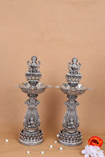 Set of 2 ornate silver mandir diya stands with deity figures and flared lamp trays