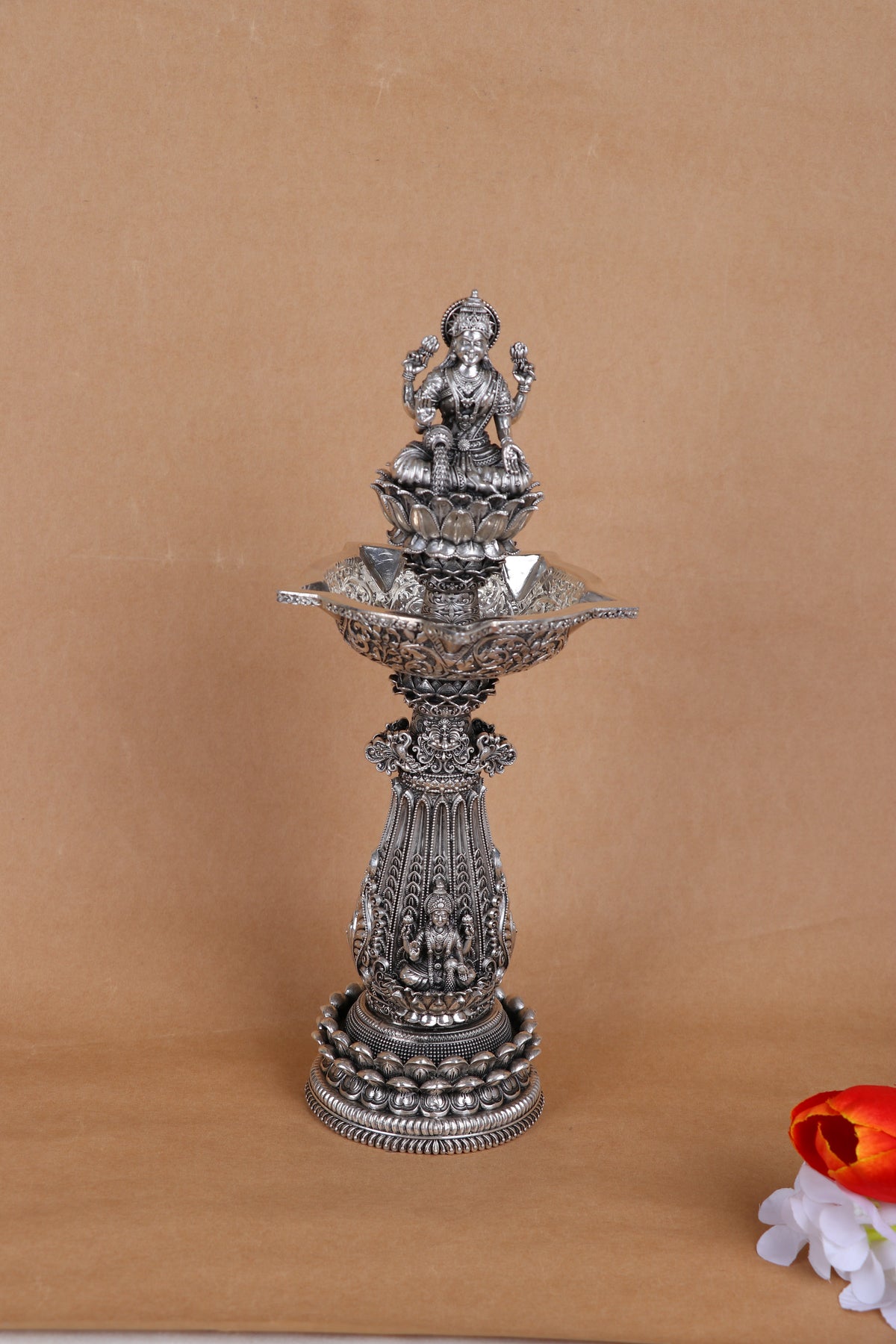 Ornate silver mandir diya stand with seated deity figure and wide top lamp bowl
